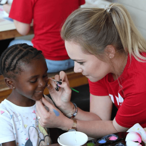 Claremont hotel staff member volunteers to paint faces at the Day Home Family Celebration