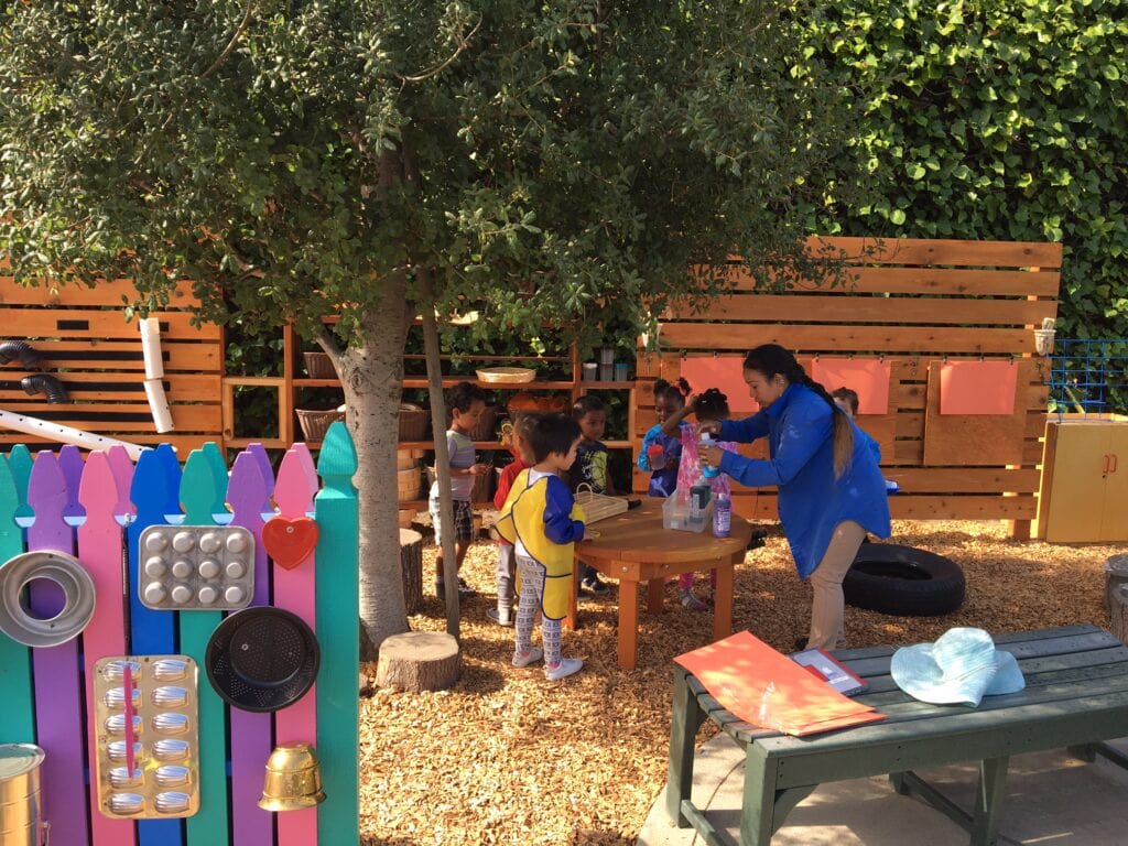 Day Home Teacher Instructs Students In Outdoor Sensory Teaching Area